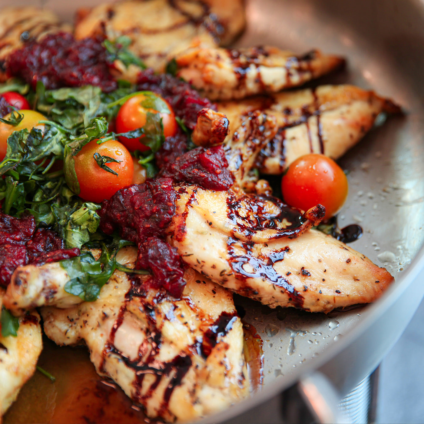 Chicken with red sauce, greens and tomatoes sautéed in pan