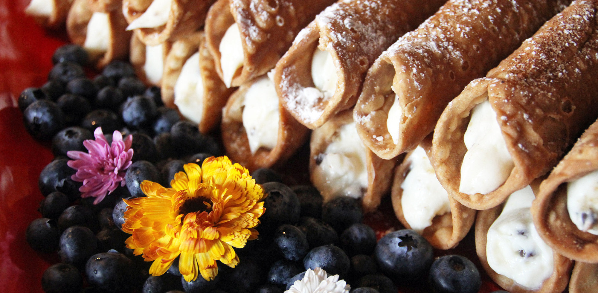 Stacked cannolis with blueberries and flower garnish