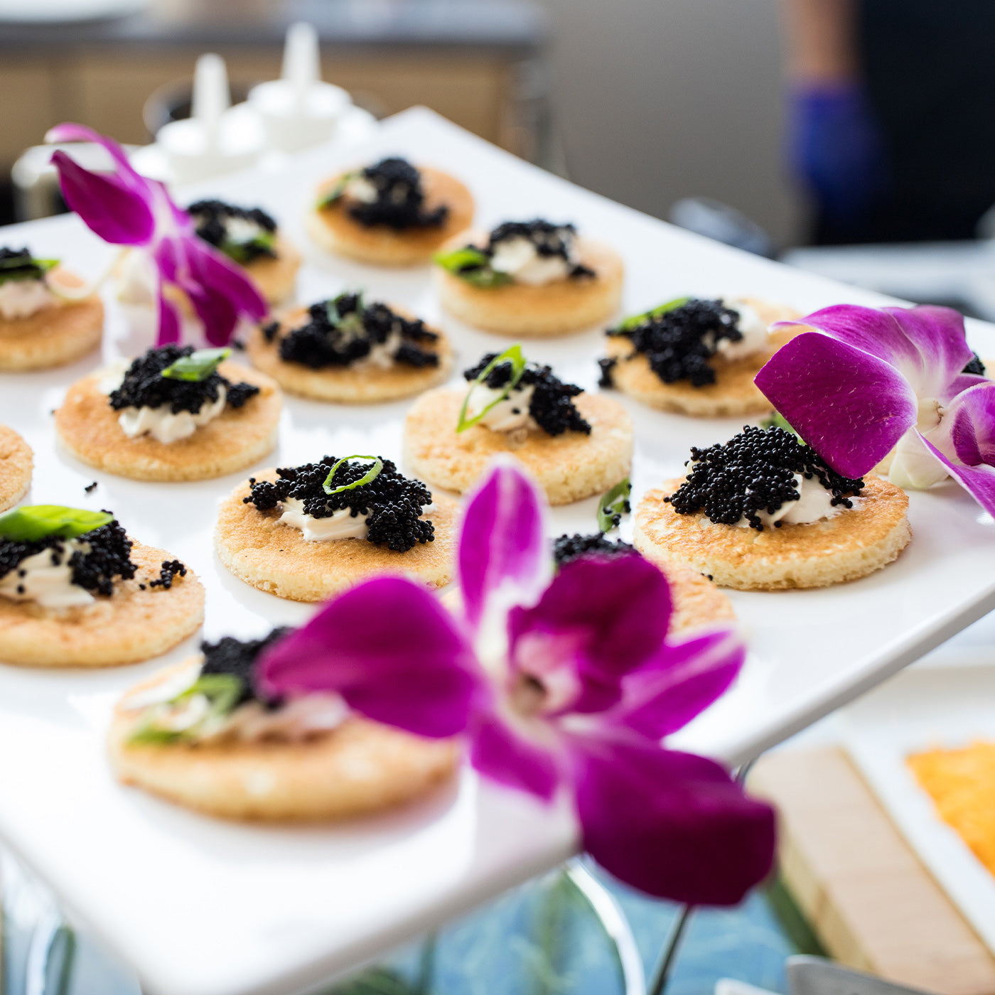 Crisps with caviar arranged on plate with flowers as garnish